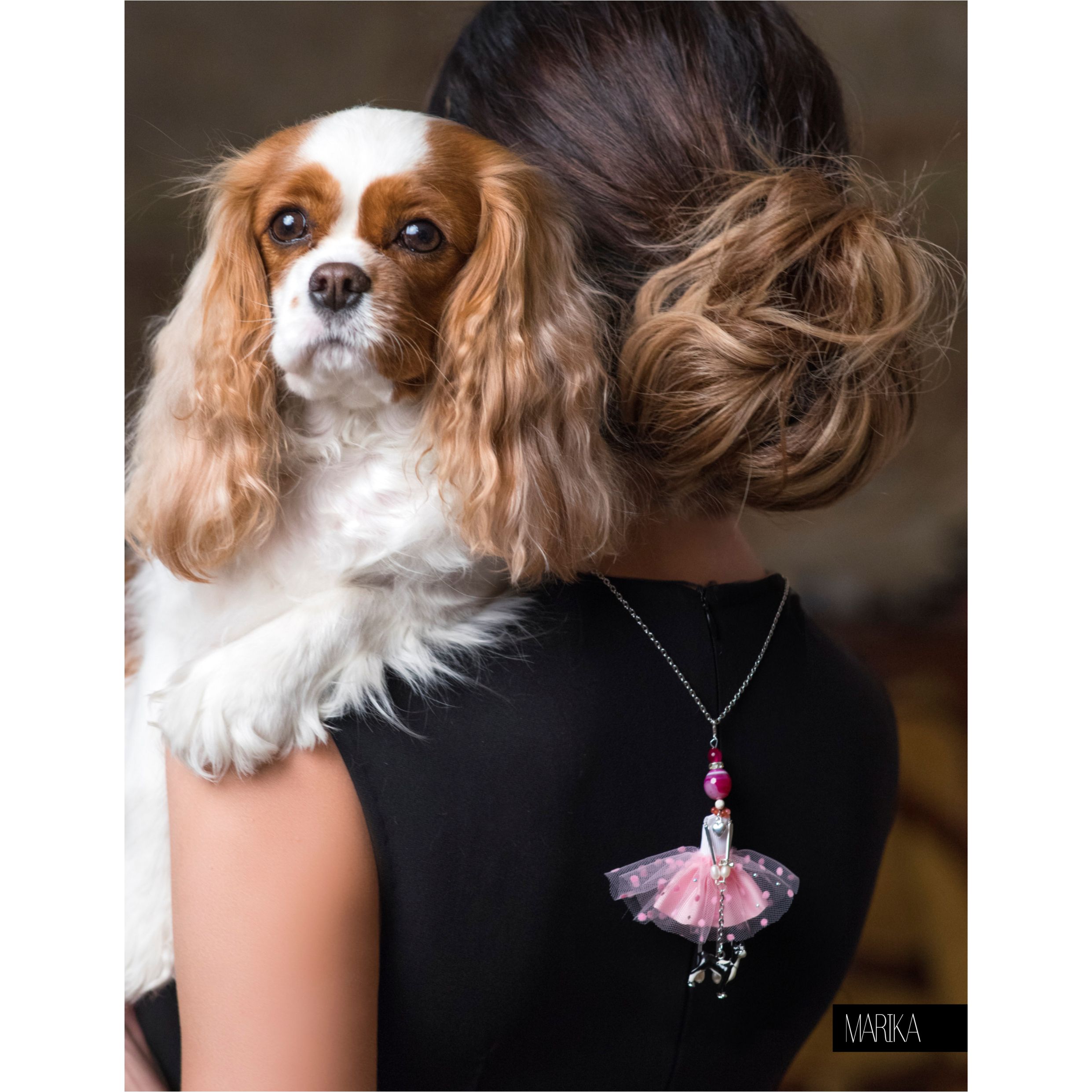 Muñeca-colgante SARANA® en color rosa de la colección «Devoción» junto a un spaniel
