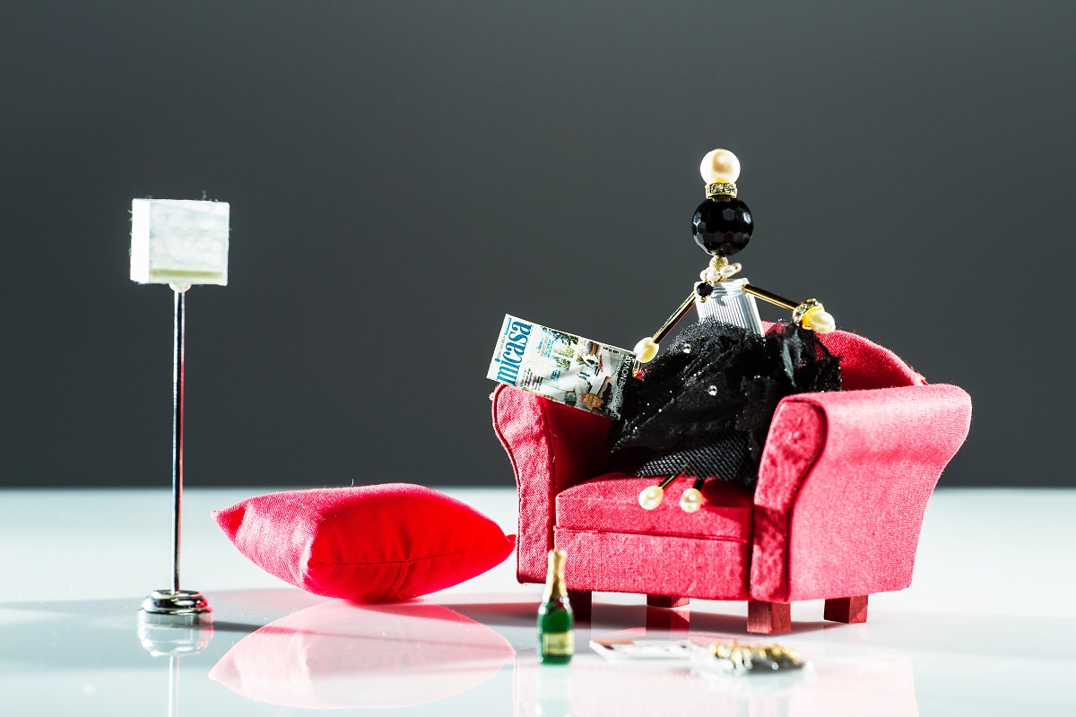 Muñeca-colgante única SARANA® con ágata negra y perlas, vestida con falda negra leyendo una revista