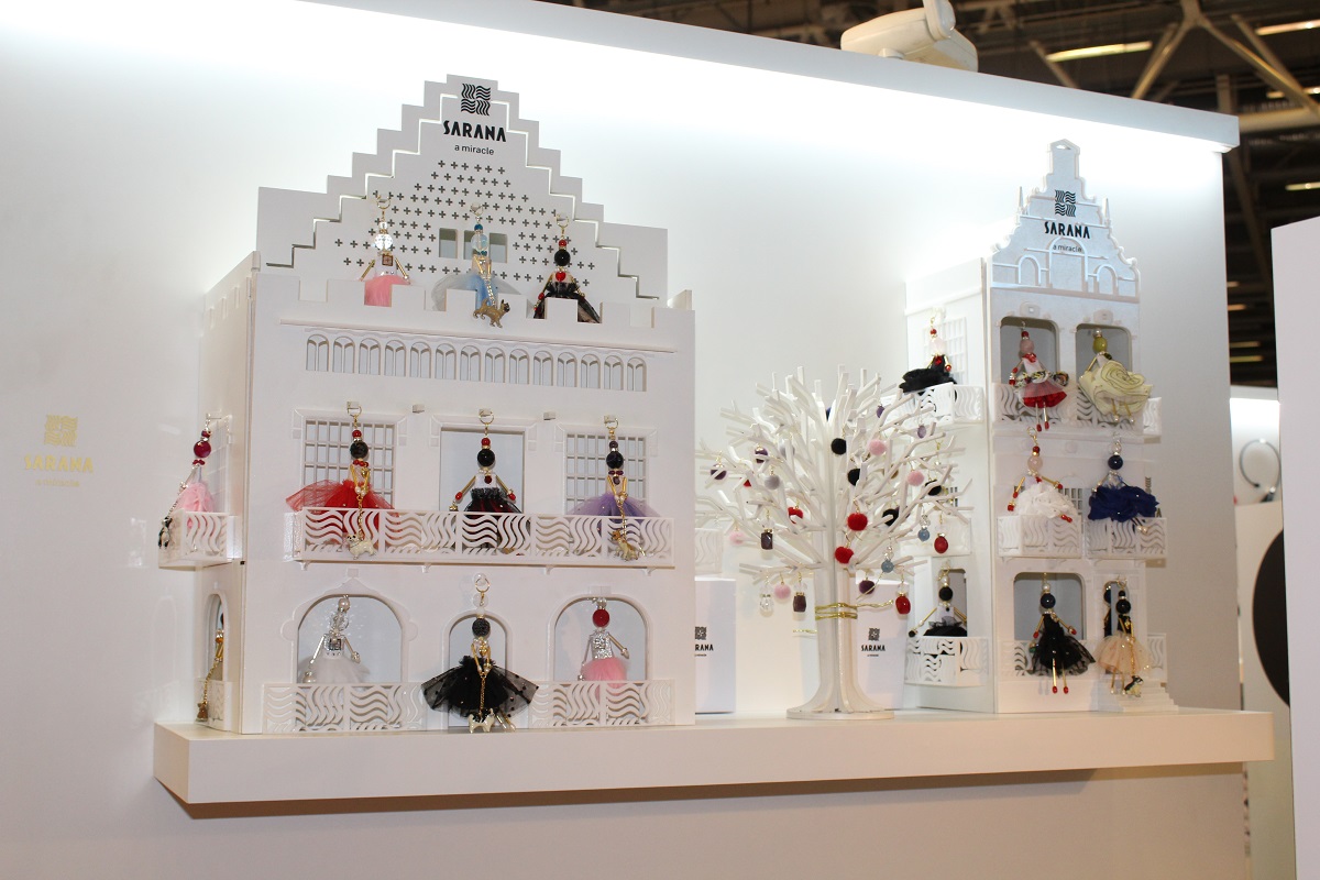 House-shaped exhibition stand with balconies displaying SARANA® jewelry doll pendants from different collections
